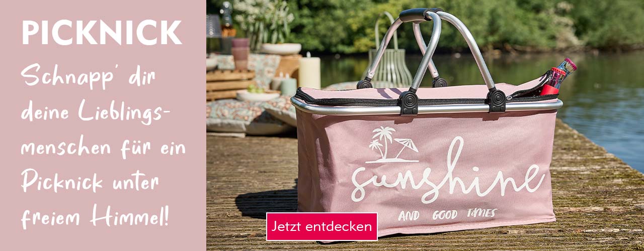 Ein rosafarbener Picknickkorb auf einem Holzsteg bei Sonnenschein verlinkt auf die Kategorie Picknick